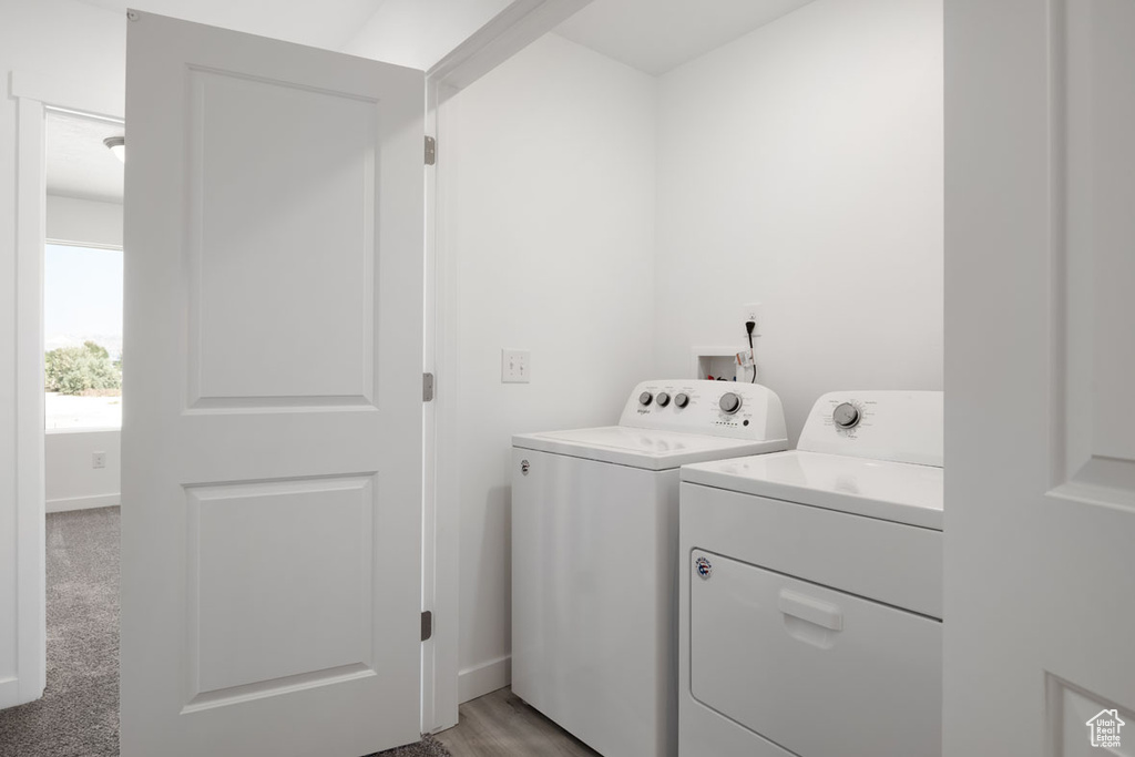 Laundry room with washing machine and dryer, light carpet, and washer hookup