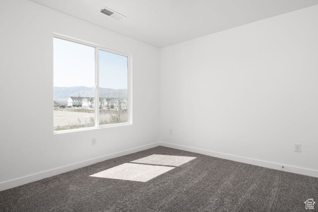 Spare room featuring plenty of natural light, a mountain view, and dark colored carpet