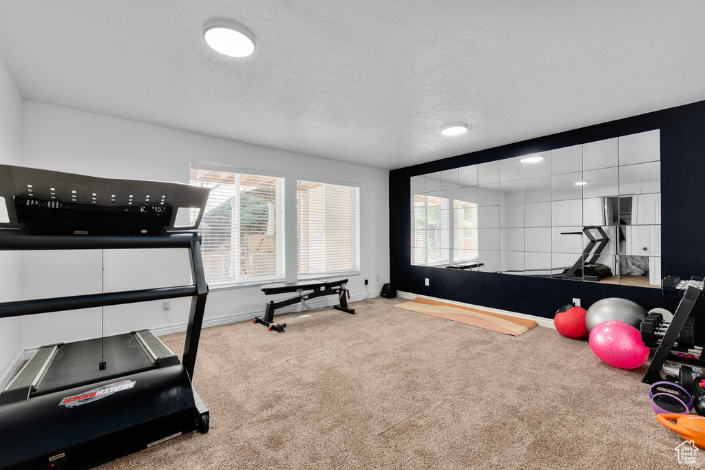 Exercise room with a textured ceiling and light carpet