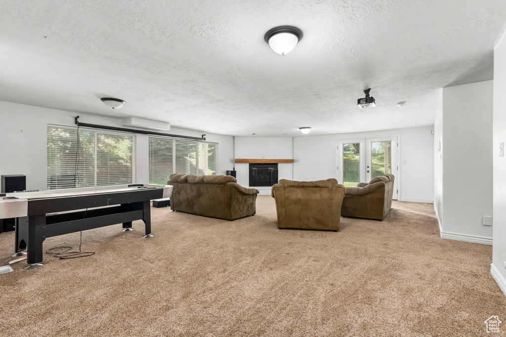 Living room featuring french doors, light colored carpet, a wall mounted air conditioner, and a textured ceiling