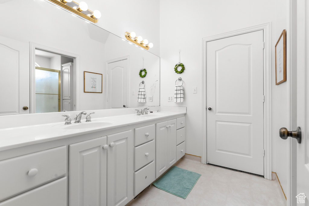 Bathroom with dual sinks, large vanity, and tile floors