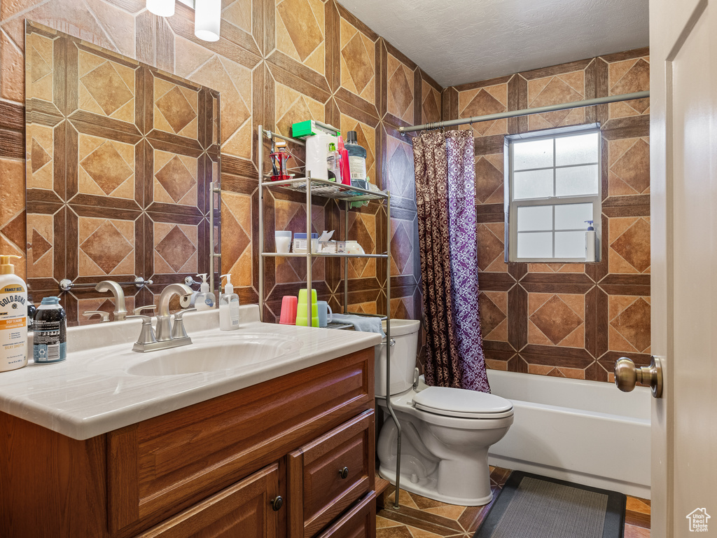 Full bathroom with toilet, tile flooring, vanity, tile walls, and shower / bathtub combination with curtain