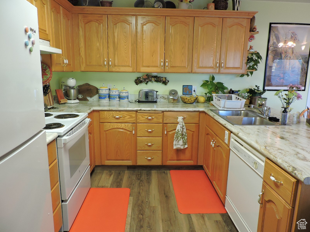 Kitchen featuring white appliances, dark hardwood / wood-style floors, light stone countertops, and sink