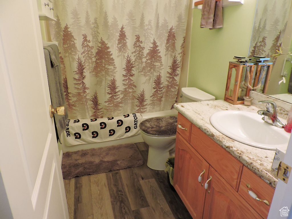 Full bathroom with toilet, shower / bath combo, vanity, and hardwood / wood-style floors