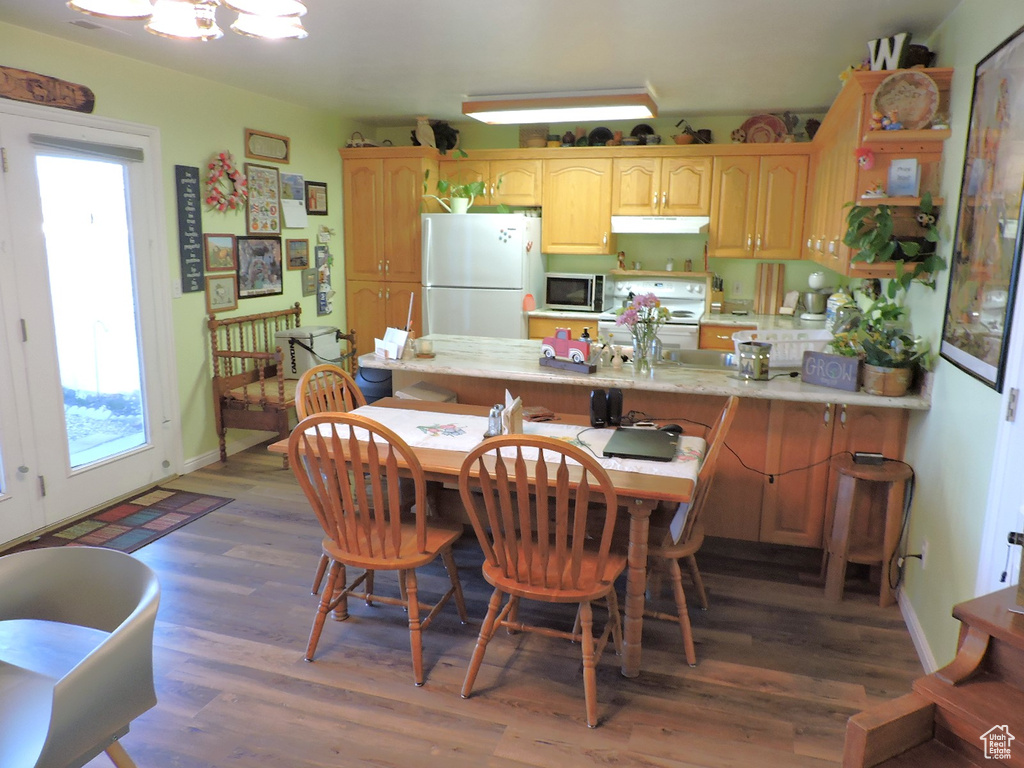 Kitchen featuring a kitchen breakfast bar, white appliances, kitchen peninsula, and dark hardwood / wood-style floors