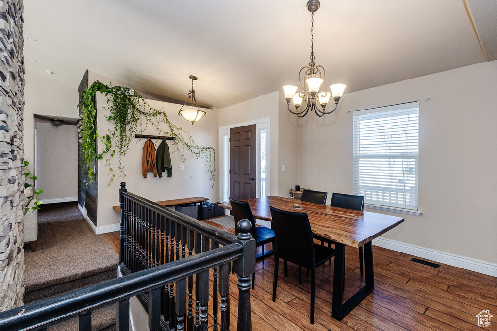 Dining room with dark hardwood / wood-style flooring, a notable chandelier, and lofted ceiling