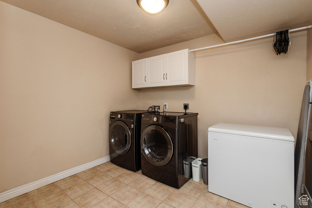 Laundry area featuring hookup for an electric dryer, light tile floors, cabinets, separate washer and dryer, and hookup for a washing machine