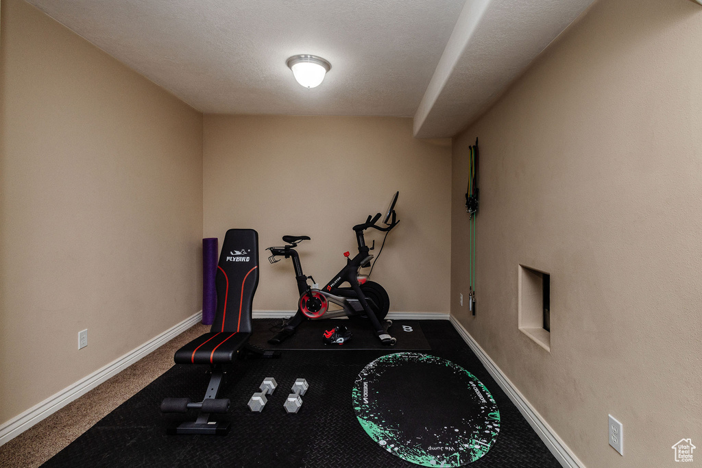 Exercise room with dark carpet and a textured ceiling