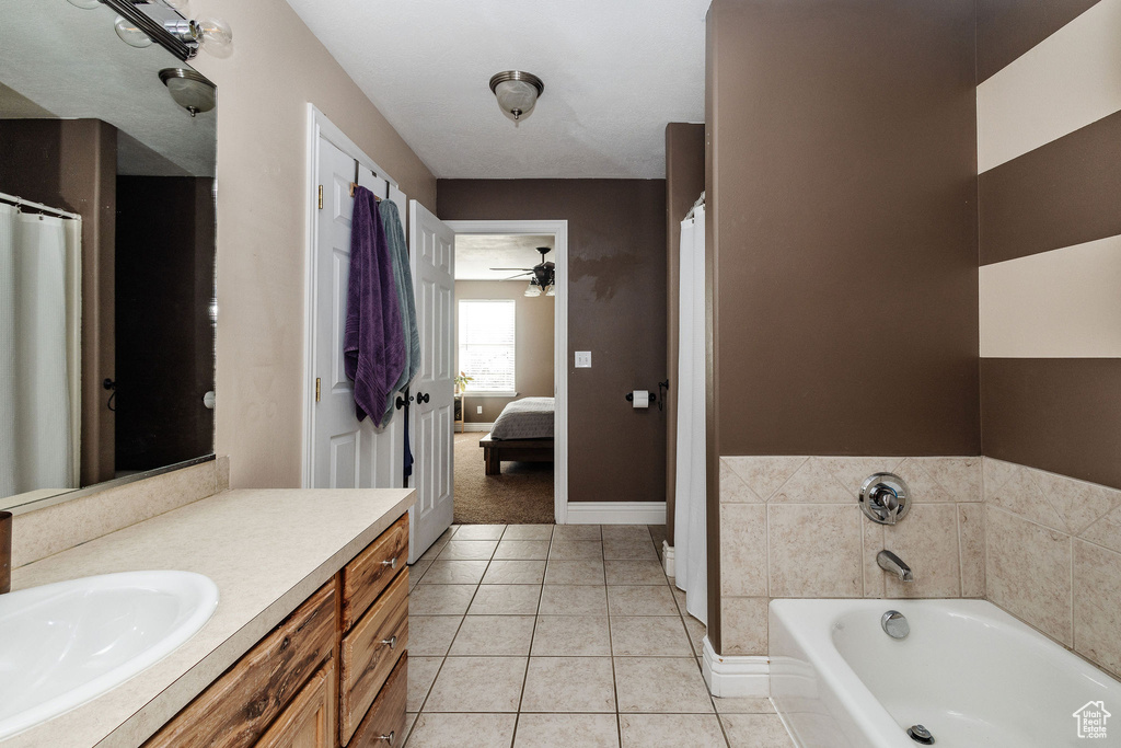 Bathroom with a bathtub, oversized vanity, ceiling fan, and tile floors
