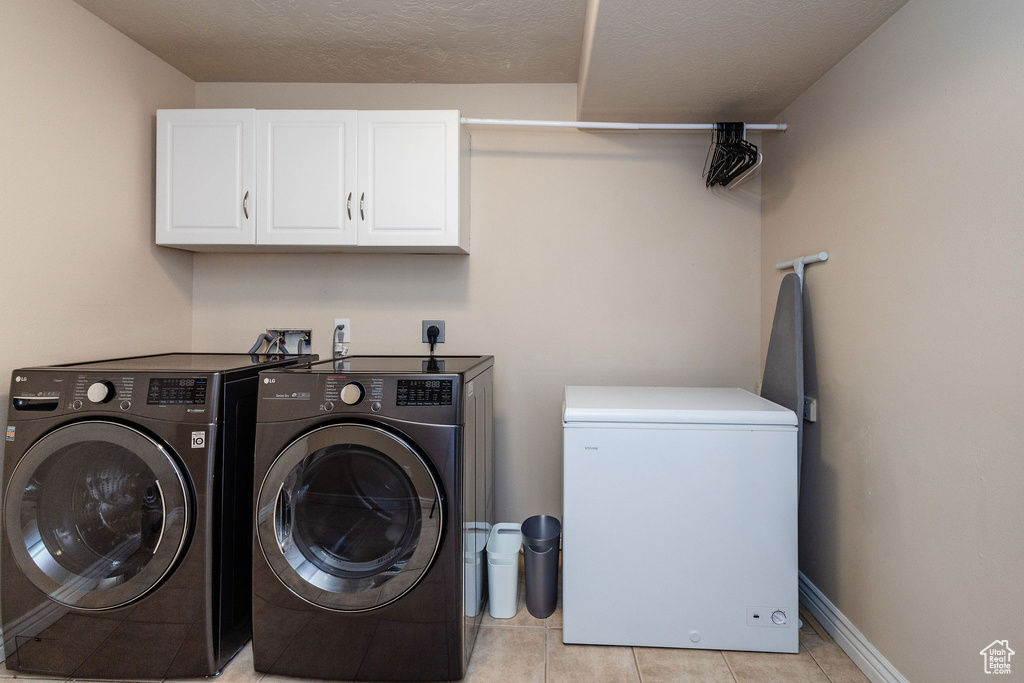 Washroom with electric dryer hookup, light tile floors, cabinets, washer and dryer, and washer hookup