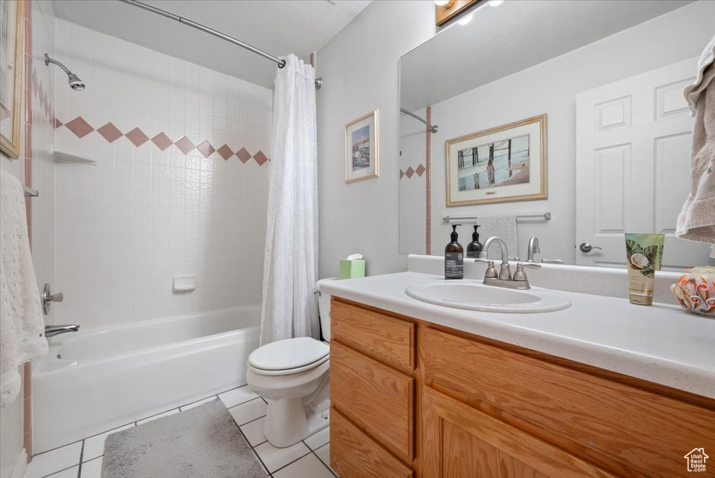 Full bathroom with toilet, tile flooring, large vanity, and shower / bath combo with shower curtain