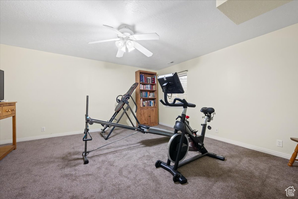 Exercise room with ceiling fan and dark carpet