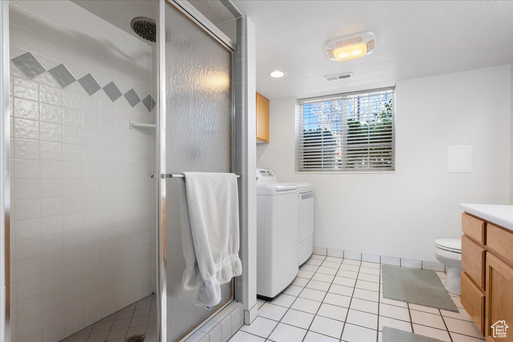Bathroom featuring toilet, washer and clothes dryer, tile flooring, vanity, and a shower with shower door
