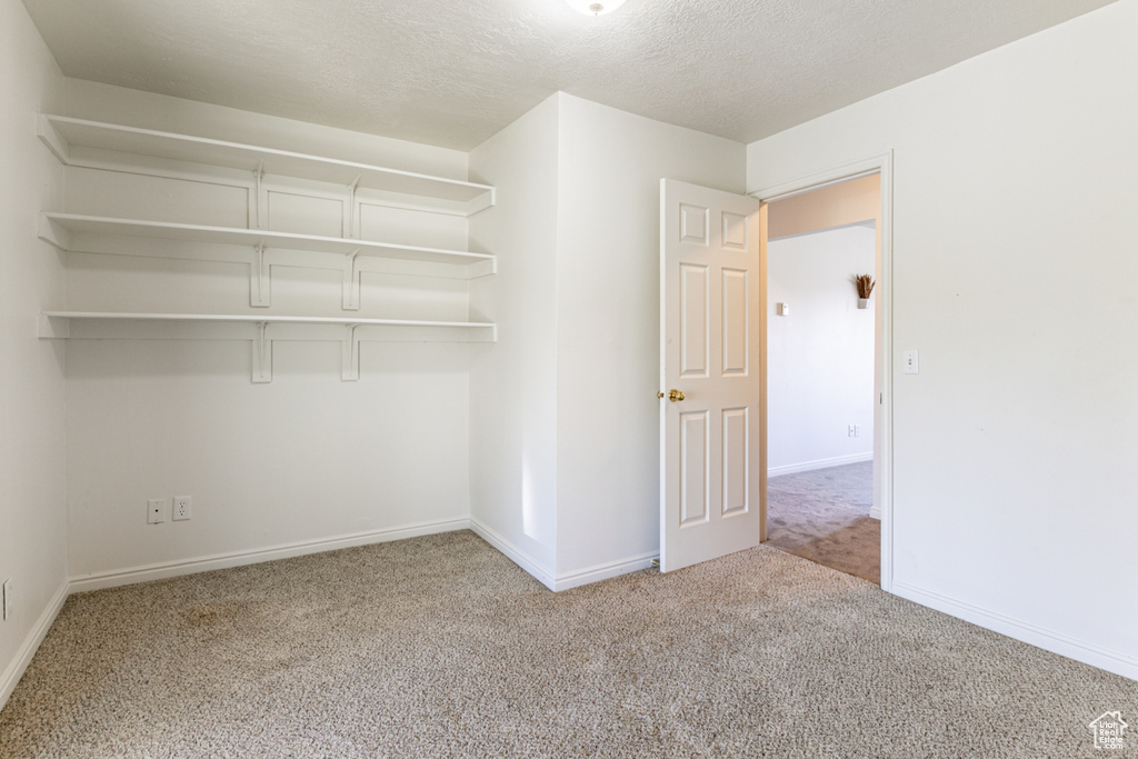 Unfurnished bedroom with a closet, light carpet, and a textured ceiling