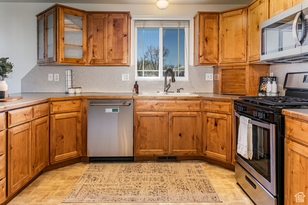 Kitchen with sink, stainless steel appliances, tasteful backsplash, and light tile flooring