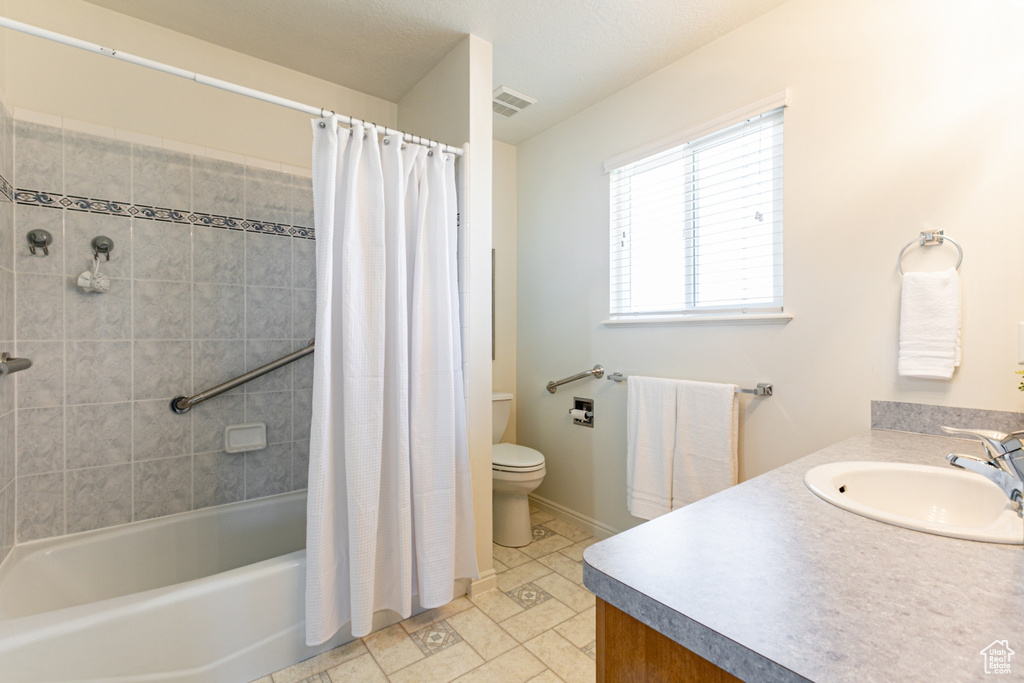 Full bathroom with shower / bathtub combination with curtain, tile flooring, toilet, and vanity