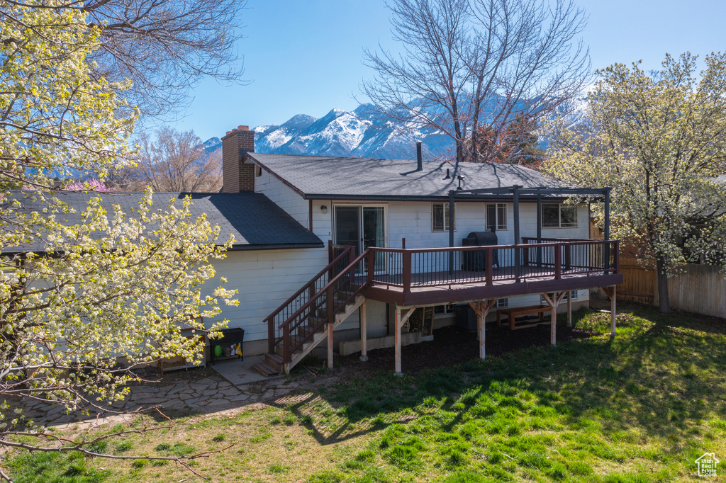 Rear view of property with a deck with mountain view and a lawn