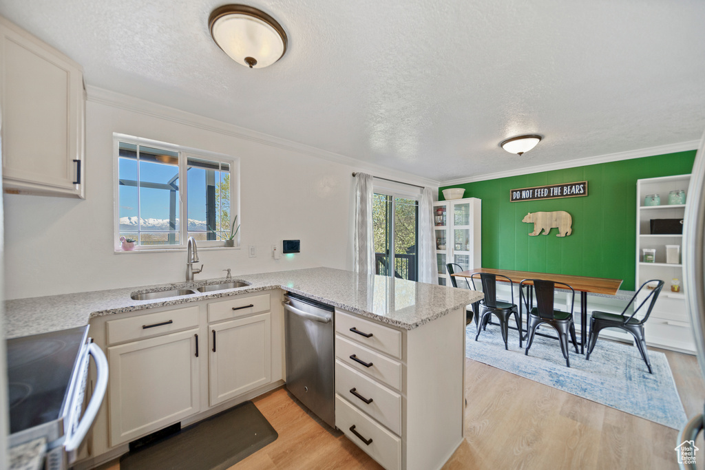 Kitchen featuring range, stainless steel dishwasher, kitchen peninsula, light hardwood / wood-style flooring, and sink