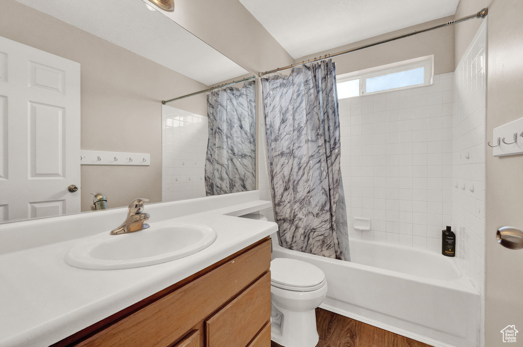 Full bathroom with shower / bath combination with curtain, toilet, large vanity, and hardwood / wood-style flooring