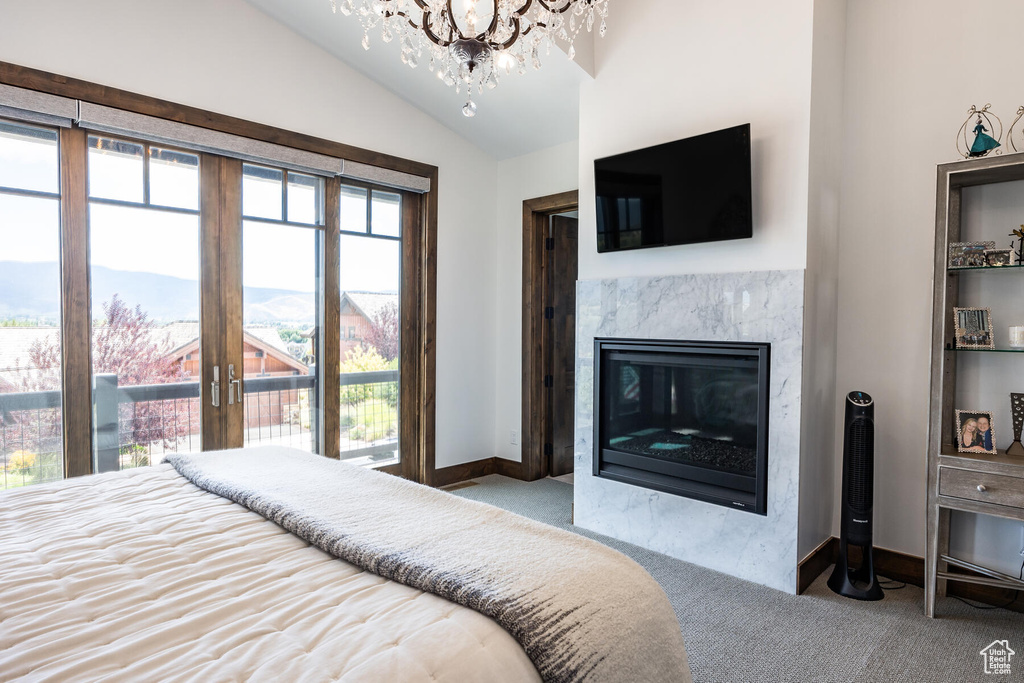 Bedroom featuring light colored carpet, a notable chandelier, lofted ceiling, and multiple windows