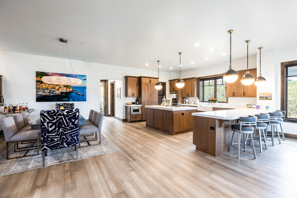 Kitchen with a breakfast bar, kitchen peninsula, pendant lighting, and light hardwood / wood-style flooring