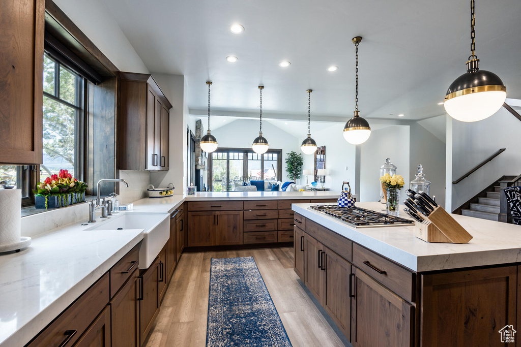 Kitchen with light hardwood / wood-style flooring, stainless steel gas cooktop, lofted ceiling, and plenty of natural light