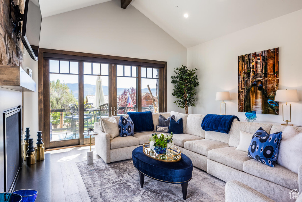 Living room featuring high vaulted ceiling, hardwood / wood-style floors, and beamed ceiling