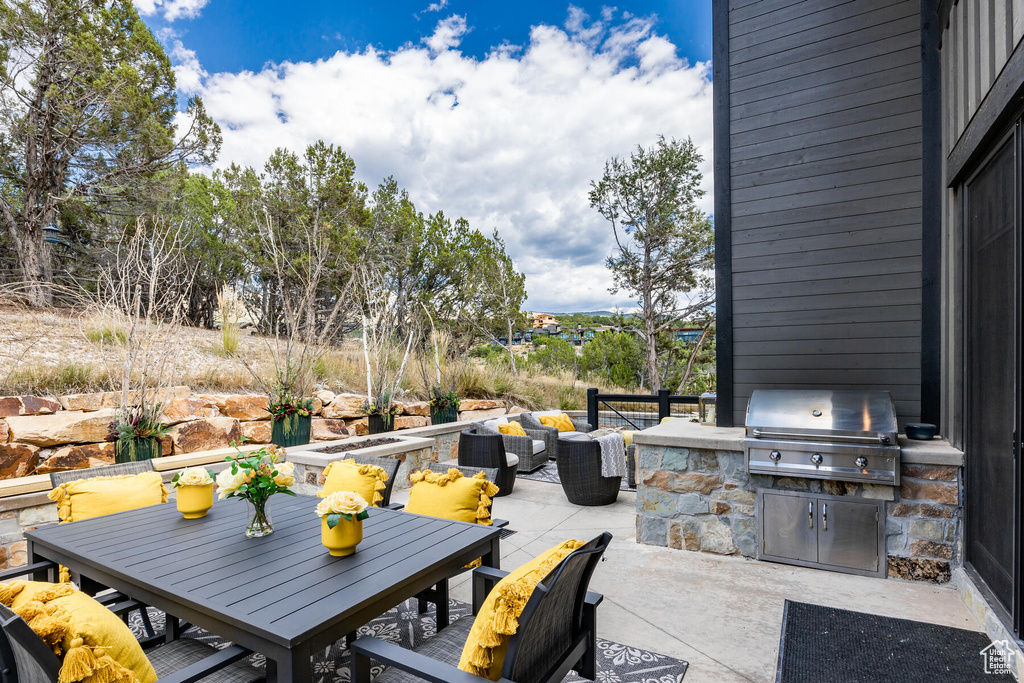 View of patio featuring area for grilling, grilling area, and an outdoor living space with a fire pit