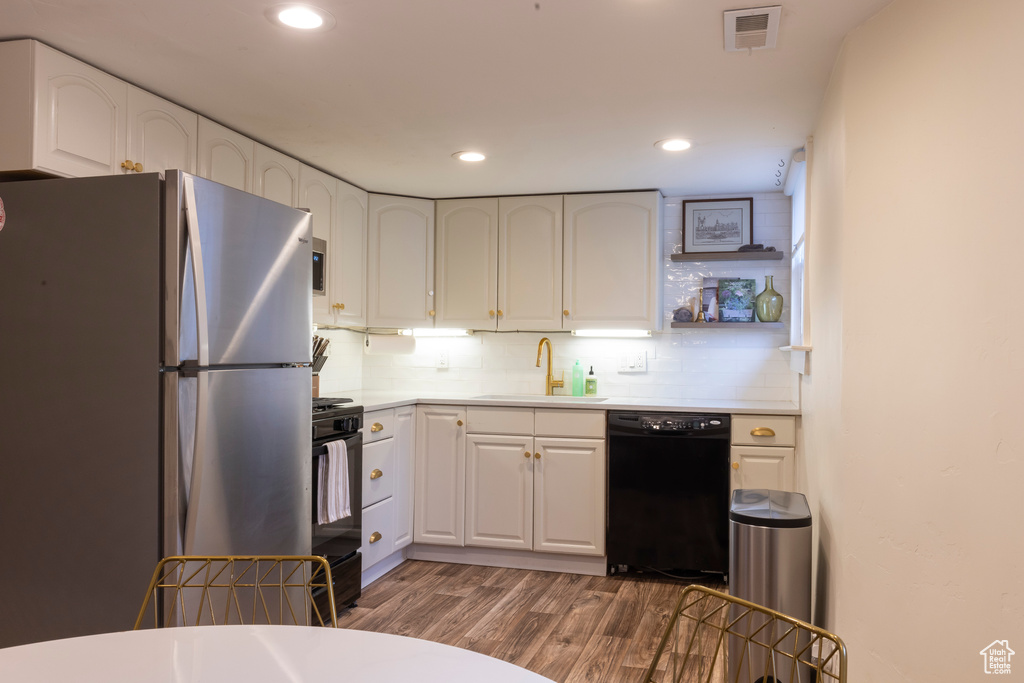Kitchen featuring black dishwasher, white cabinets, dark hardwood / wood-style floors, and stainless steel refrigerator