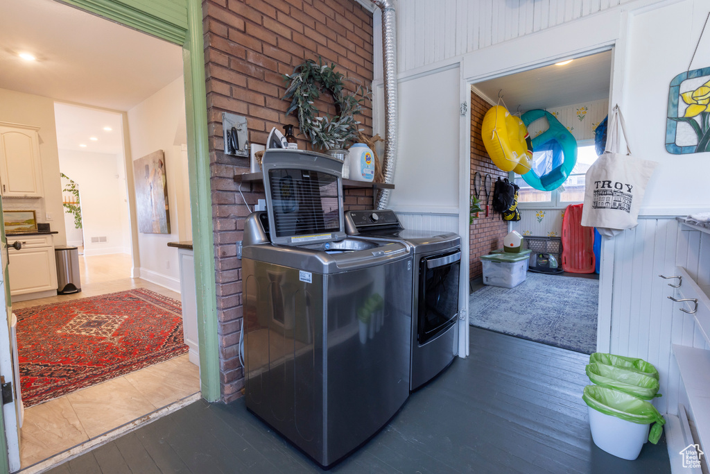 Laundry room with brick wall, dark hardwood / wood-style flooring, and washer and dryer