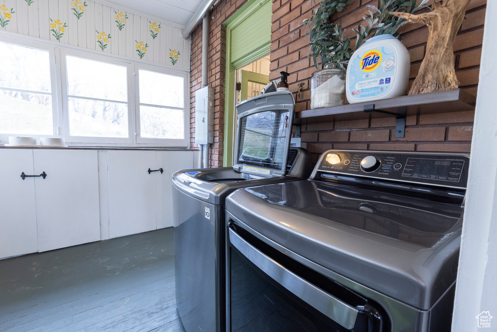 Laundry room featuring washing machine and dryer and brick wall