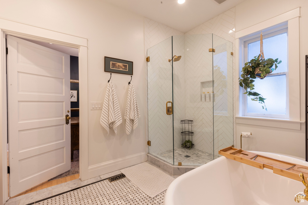 Bathroom featuring shower with separate bathtub, plenty of natural light, tile flooring, and sink