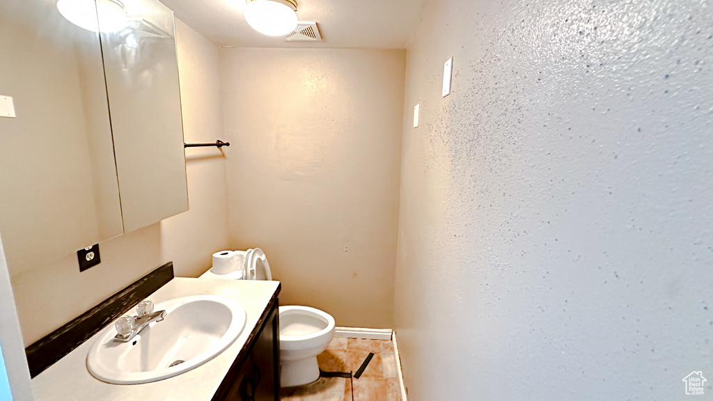 Bathroom featuring toilet, large vanity, and tile floors