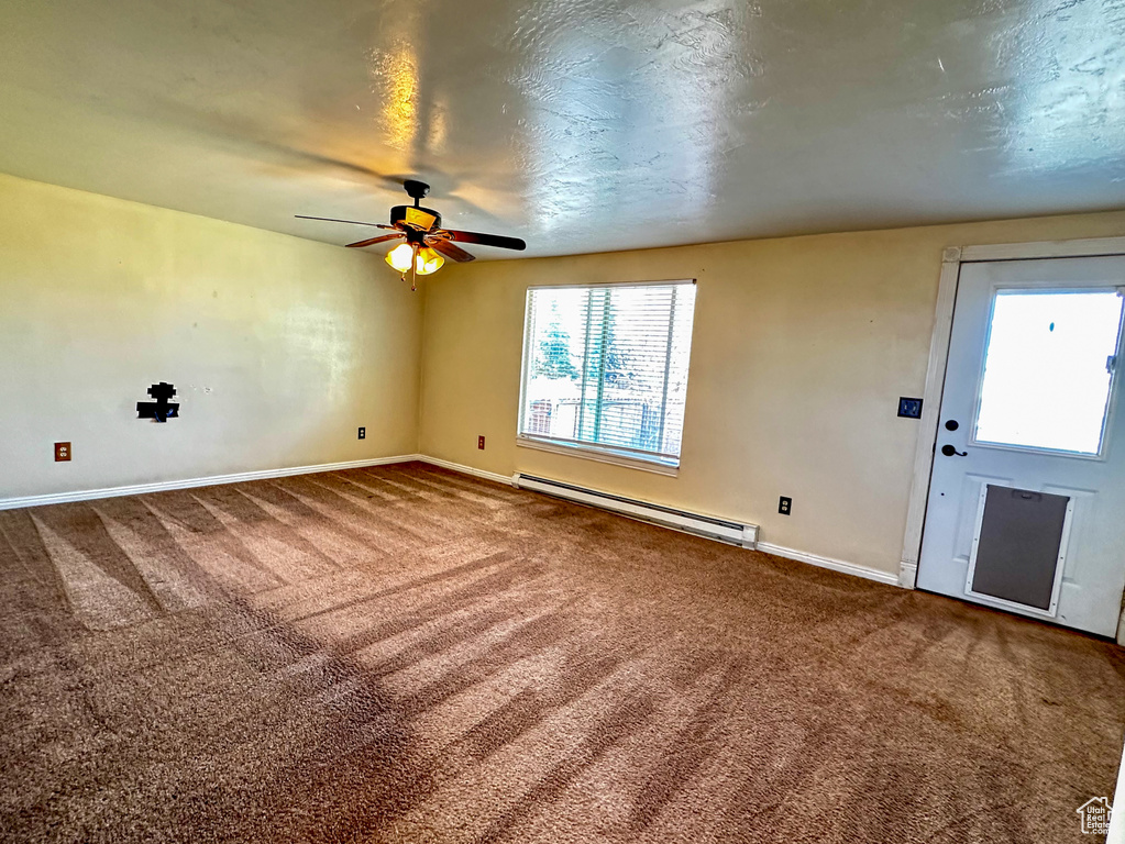 Carpeted spare room featuring ceiling fan and a baseboard radiator
