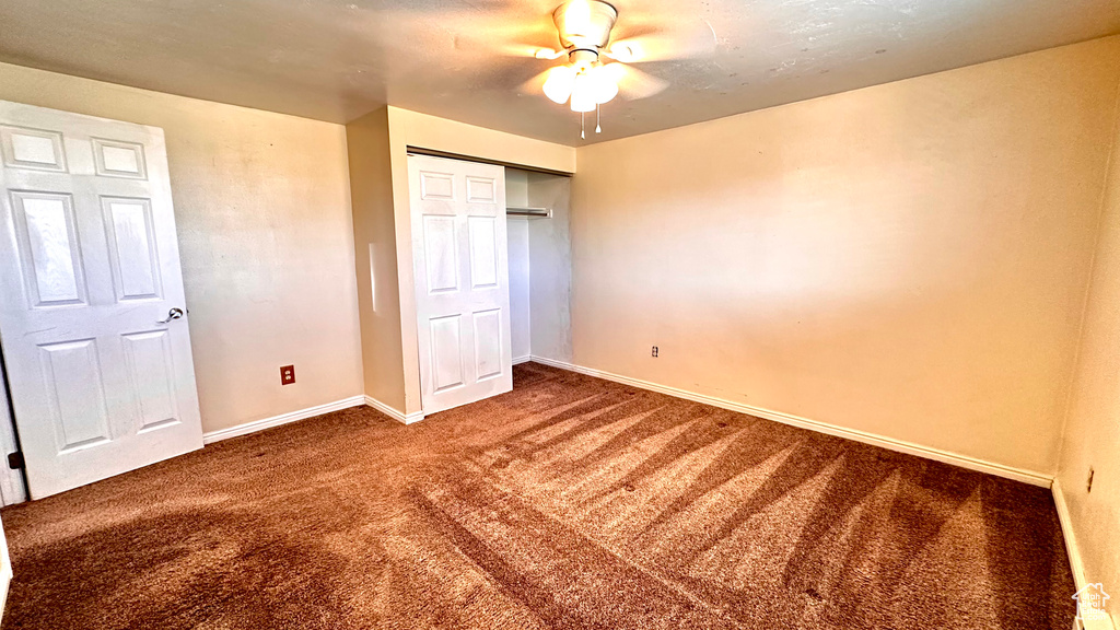 Unfurnished bedroom featuring ceiling fan, a closet, and dark colored carpet