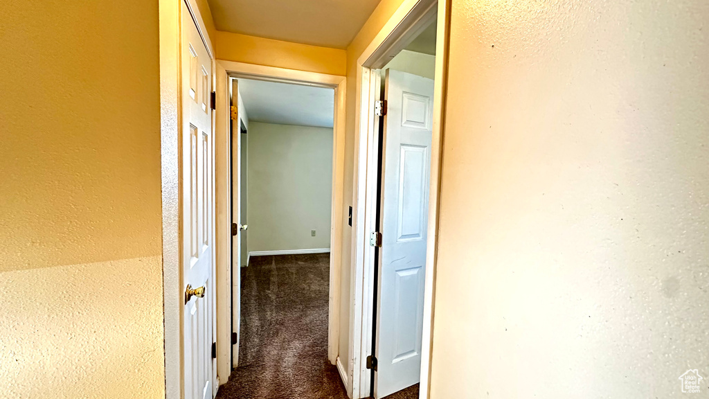 Corridor featuring dark carpet