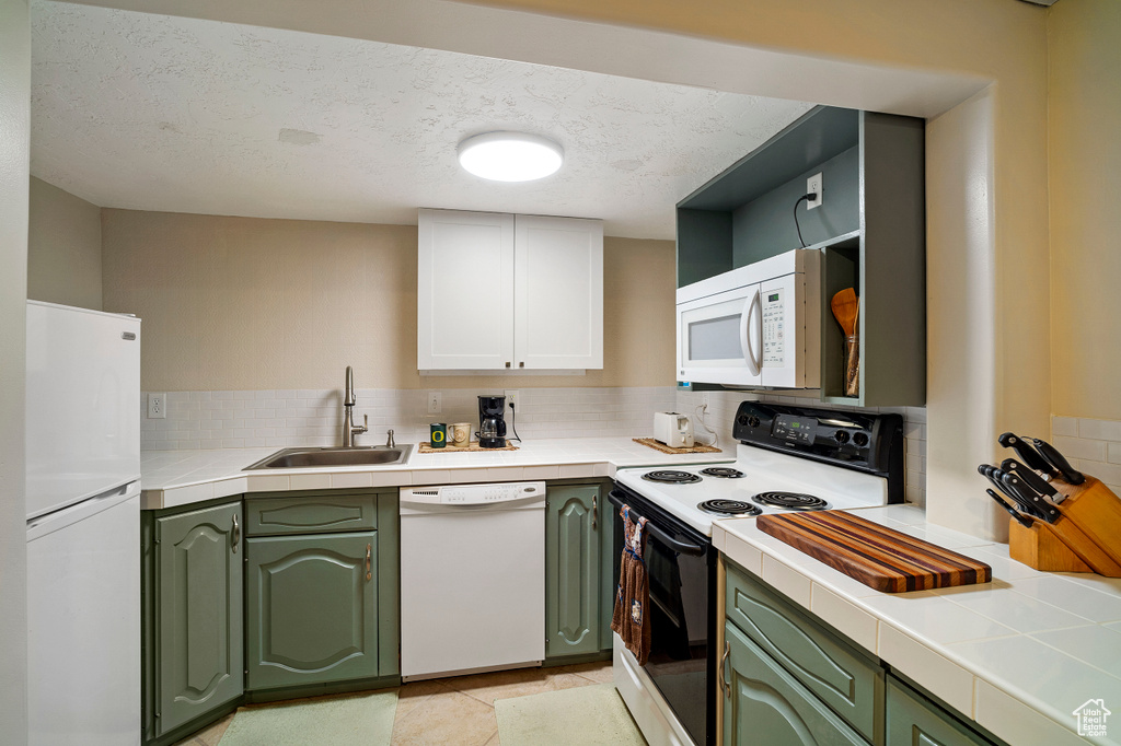 Kitchen featuring white appliances, sink, and tasteful backsplash