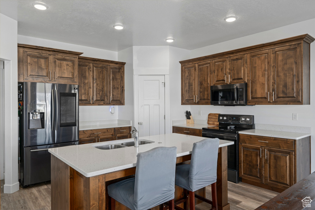 Kitchen with light hardwood / wood-style flooring, sink, an island with sink, and stainless steel appliances
