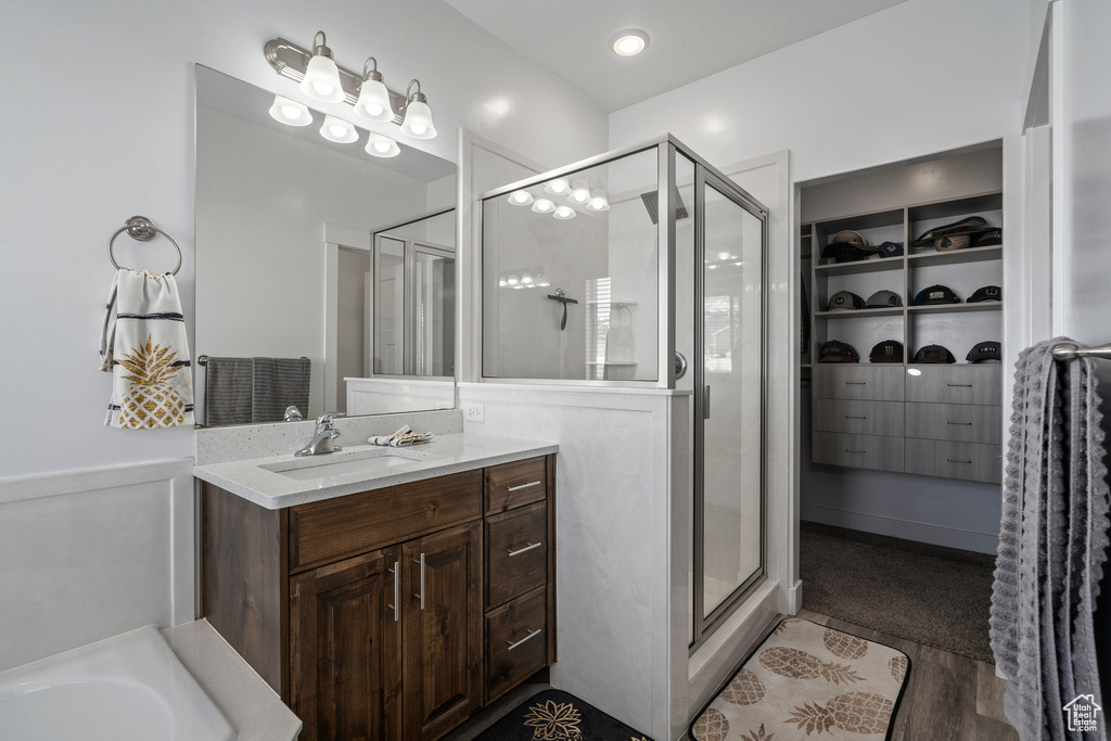 Bathroom featuring plus walk in shower, hardwood / wood-style floors, and vanity