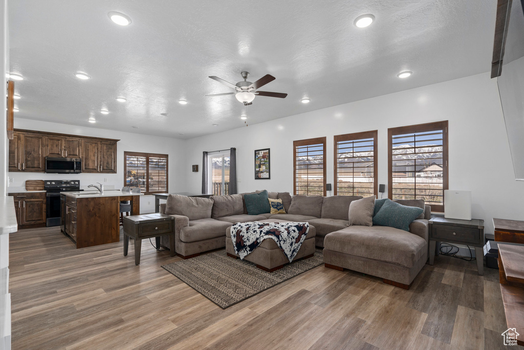 Living room featuring ceiling fan, sink, hardwood / wood-style flooring, and a healthy amount of sunlight