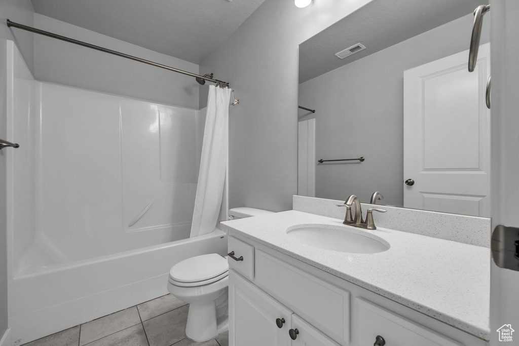 Full bathroom featuring vanity with extensive cabinet space, tile floors, toilet, and shower / tub combo