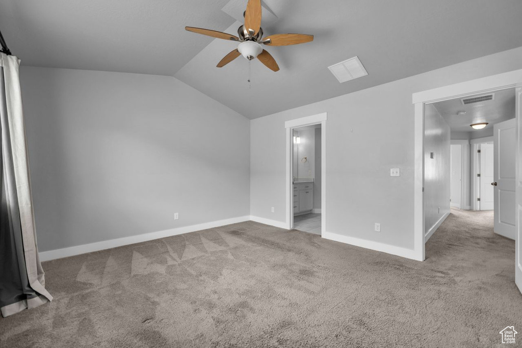 Unfurnished bedroom featuring ceiling fan, connected bathroom, light carpet, and vaulted ceiling