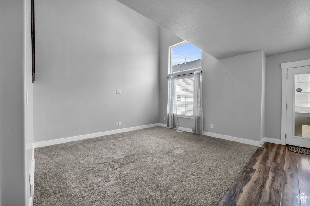 Empty room with dark colored carpet and plenty of natural light