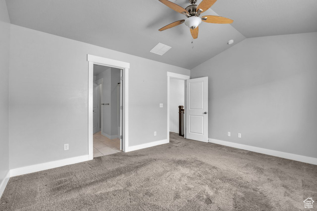 Unfurnished bedroom featuring lofted ceiling, ceiling fan, ensuite bathroom, and light colored carpet