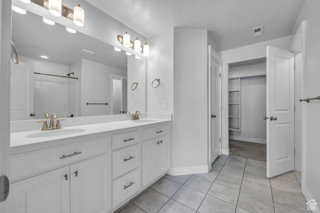 Bathroom featuring dual sinks, large vanity, and tile floors