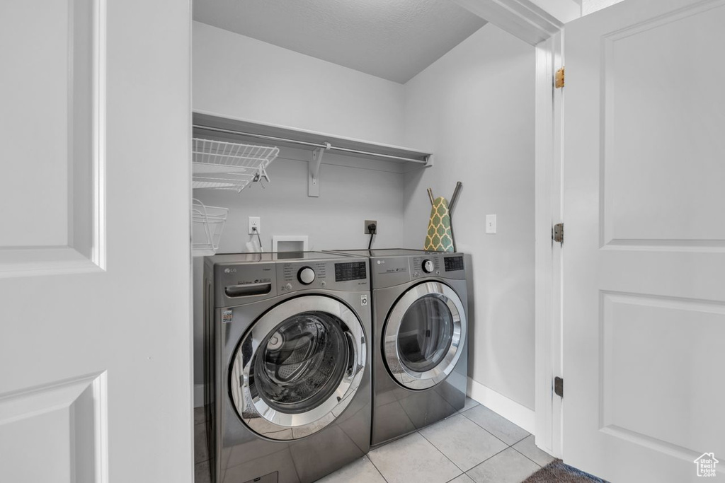 Laundry room featuring electric dryer hookup, hookup for a washing machine, light tile floors, and washer and clothes dryer