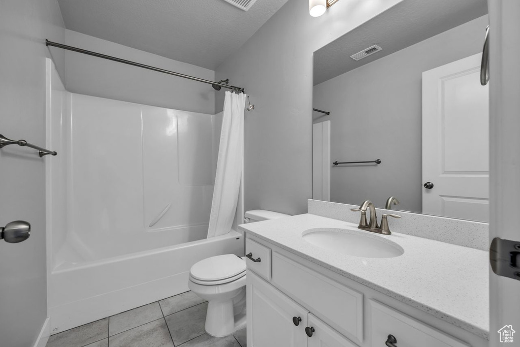 Full bathroom with tile flooring, toilet, shower / bath combo, and vanity with extensive cabinet space