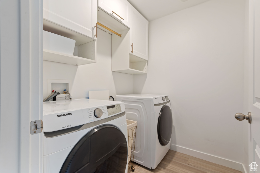 Laundry area featuring cabinets, independent washer and dryer, light hardwood / wood-style floors, and hookup for a washing machine