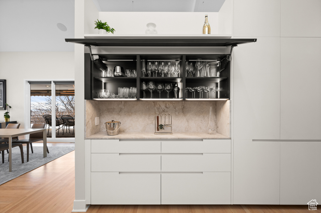 Bar featuring light wood-type flooring and white cabinets