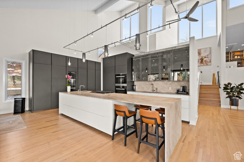 Kitchen with a towering ceiling, sink, backsplash, and a breakfast bar area